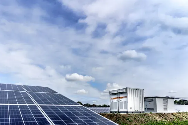 Containerised battery storage and power conversion units installed beside a ground-mounted solar array